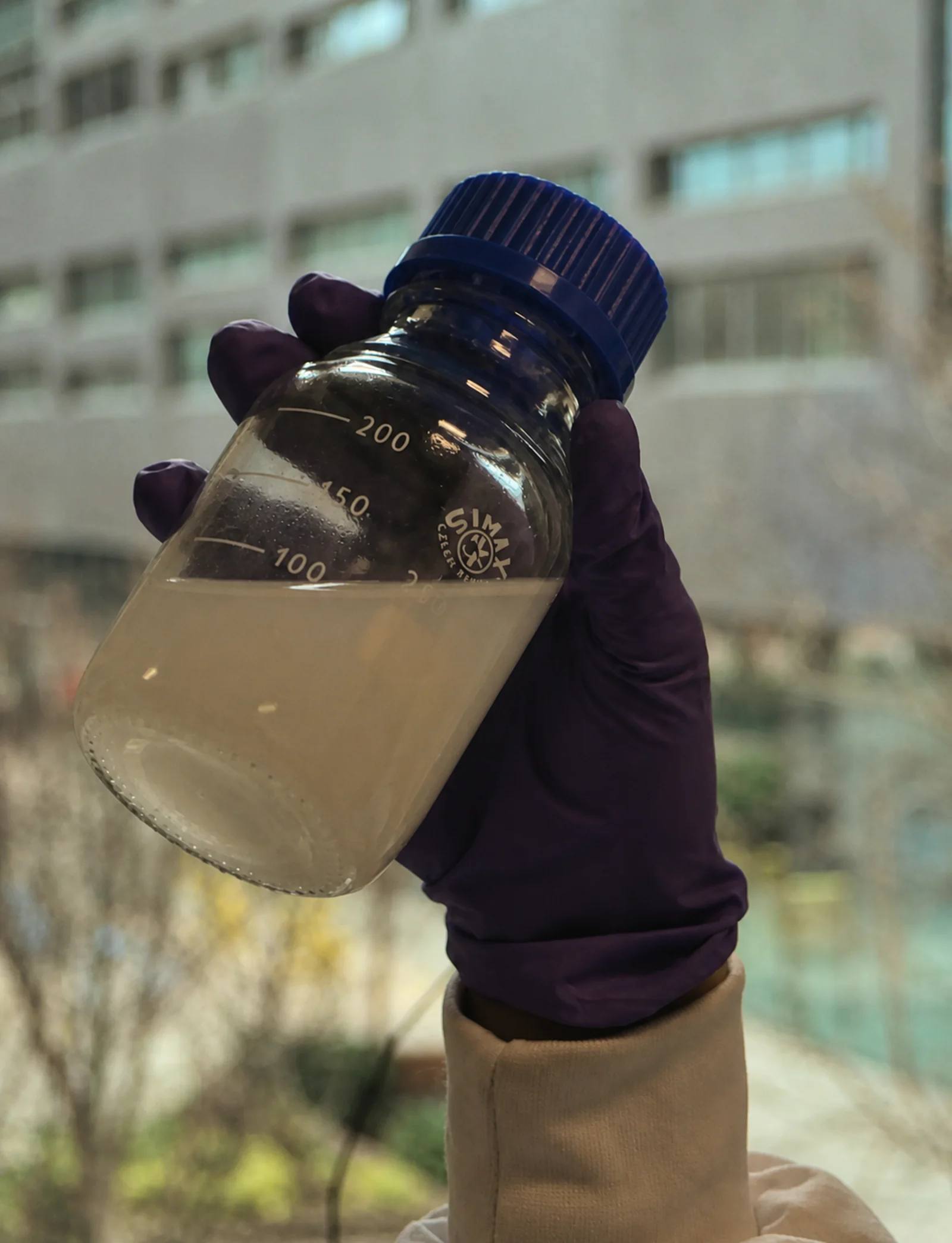 A Gennate scientist inspecting a nanoformulation bottle against the light.